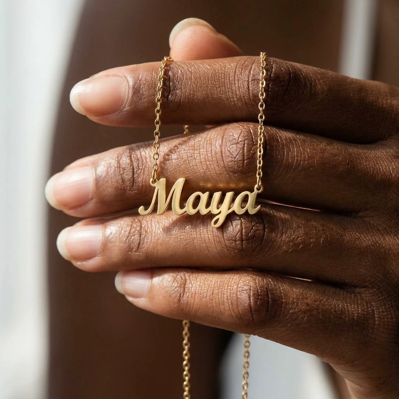 Minimalist Name Necklace pendant resting on a hand for scale, the name Maya | SKU: minimalistnn-gold