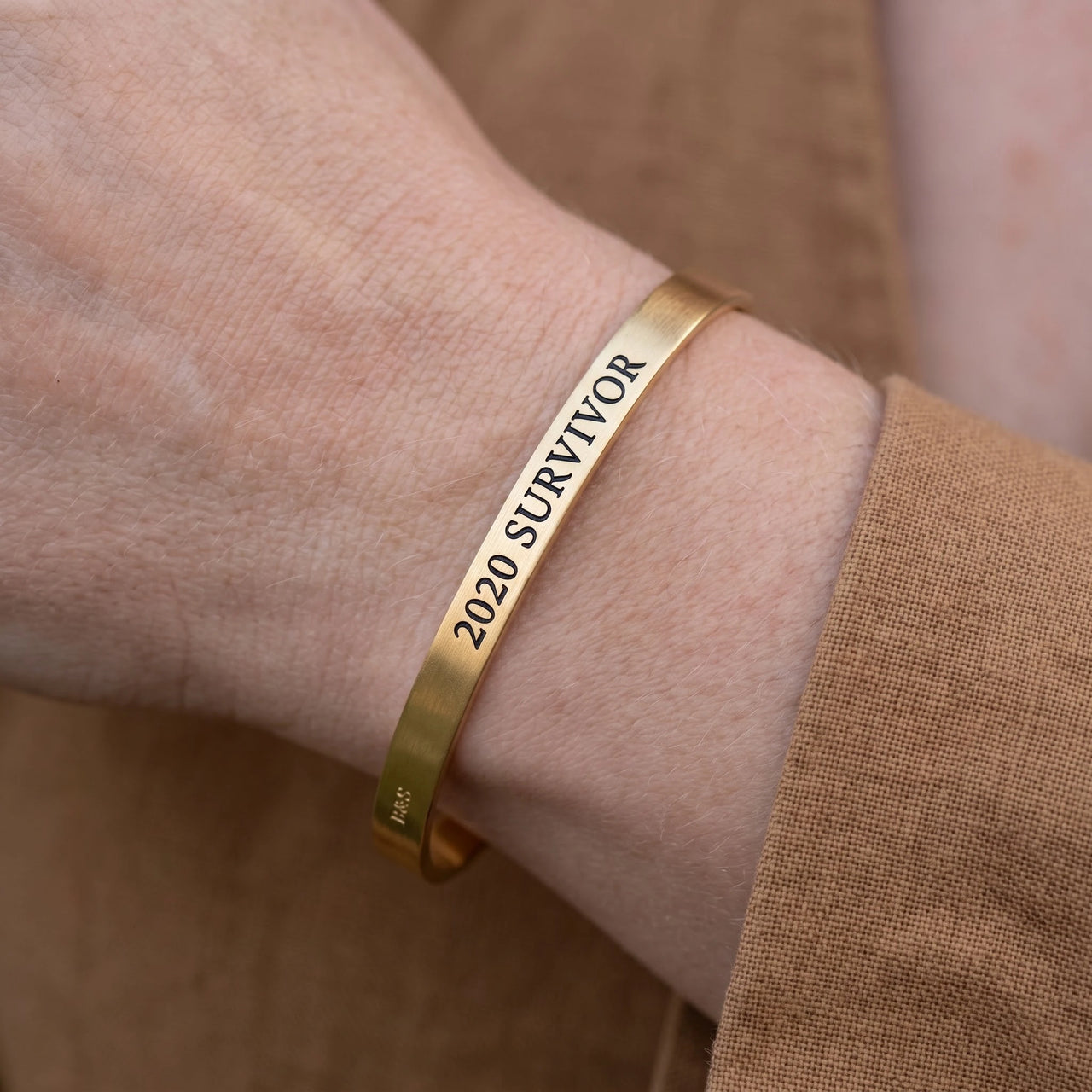 Close-up of the 2020 Survivor bracelet in gold worn | SKU: 2020s-g