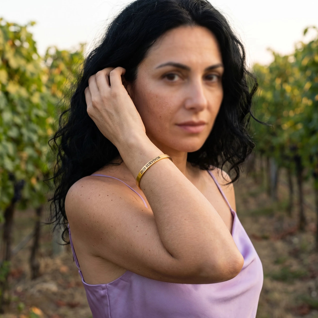 Woman gently touching her 2020 Survivor bracelet in gold | SKU: 2020s-g