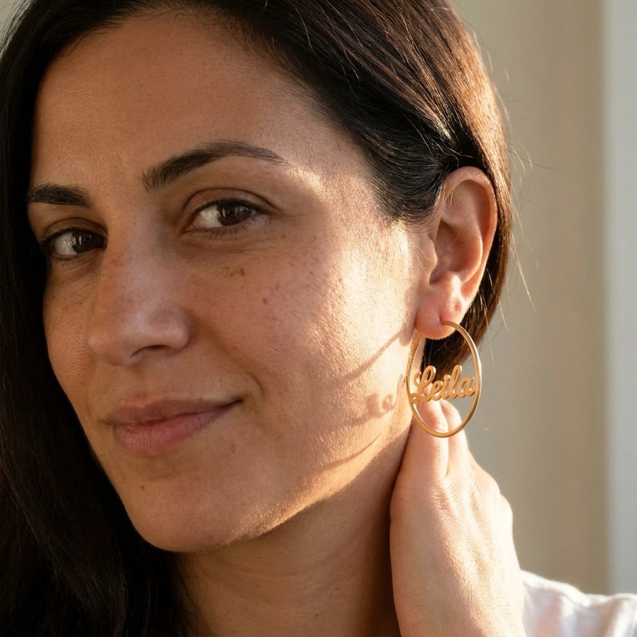 Custom Name Hoop Earrings in Gold worn on the ear, close-up on a model | SKU: name-hoop-gold-30-mm