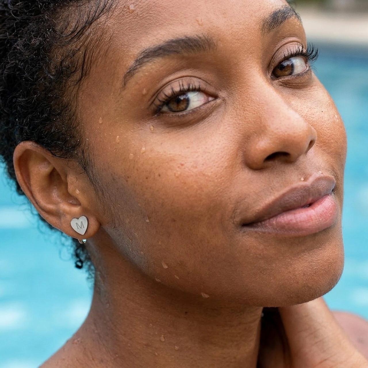 Heart Initial Stud Earrings in Silver worn in a swimming pool, waterproof 304L stainless steel | SKU: heart-initial-silver-a