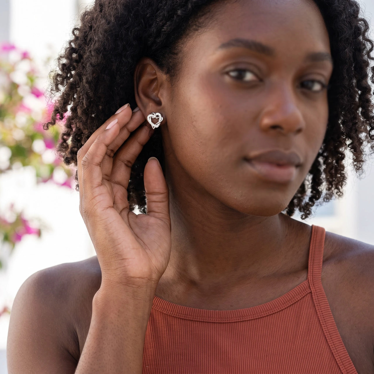 Woman gently touching her silver stud earrings | SKU: 4478648-platinum-plated-clear