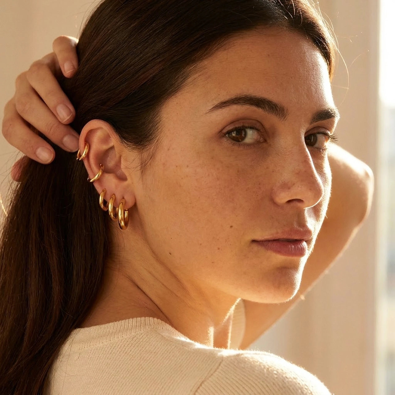 Huggie Hoop Earrings Set of 4 Pairs in Gold worn on the ear, close-up on a model | SKU: huggie-set-gold