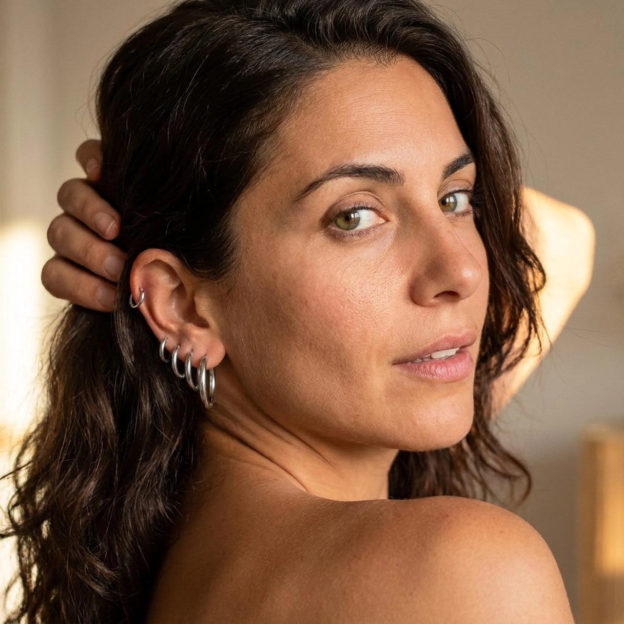 Huggie Hoop Earrings Set of 4 Pairs in Silver worn on the ear, close-up on a model | SKU: huggie-set-silver