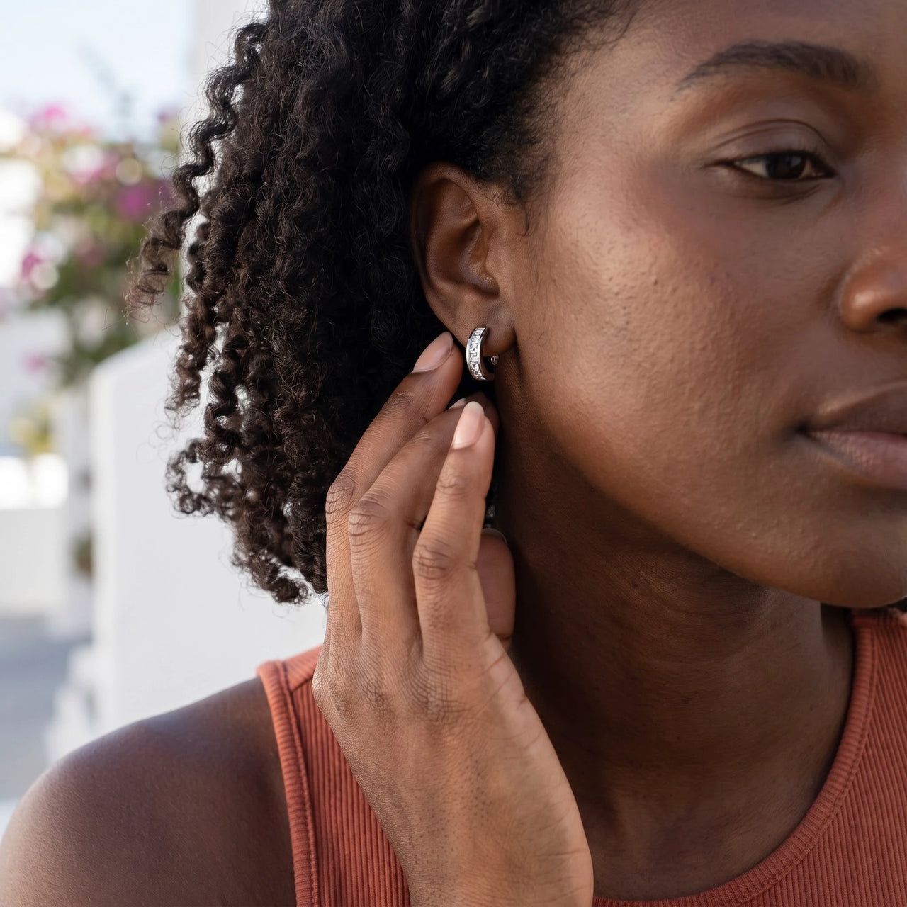 Woman gently touching her silver huggie hoop earrings | SKU: 22023999-rhodium