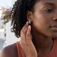 Thumbnail for Woman gently touching her silver huggie hoop earrings | SKU: 22023999-rhodium