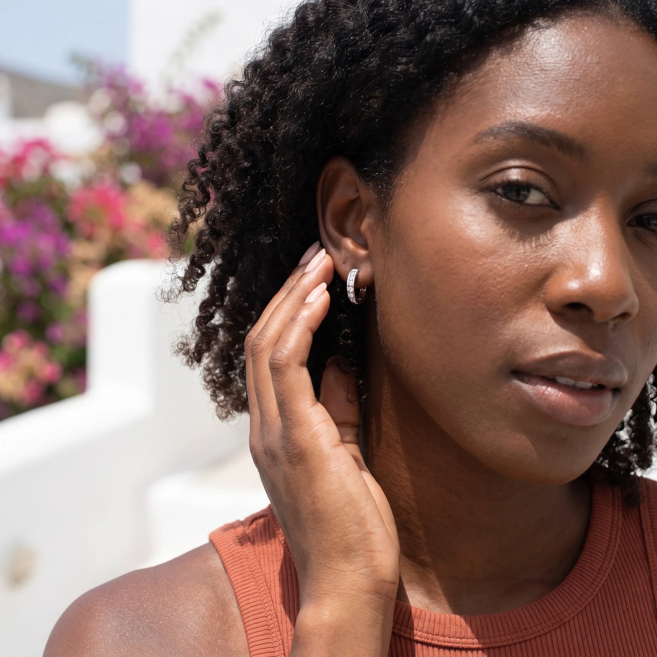 Woman gently touching her silver huggie hoop earrings | SKU: 22023999-rhodium
