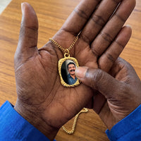 Thumbnail for Thumb warming the gold oval pendant: the hidden photo appears under the thumb while the rest stays black | SKU: TPH-OVLN-GOLD